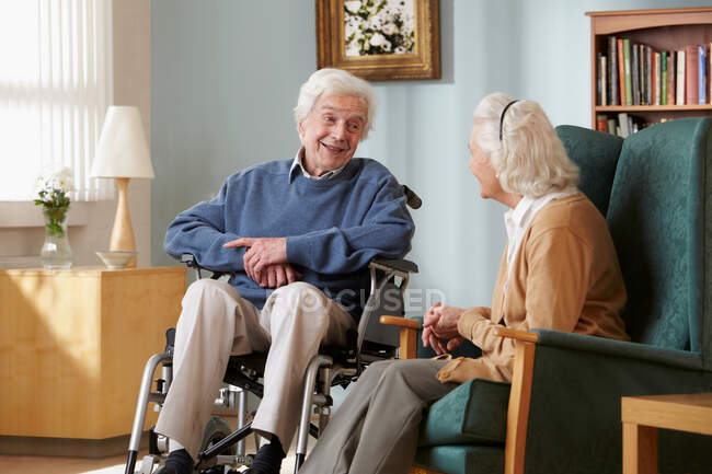 Pareja mayor en el hogar de cuidado, hombre en silla de ruedas - foto de stock
