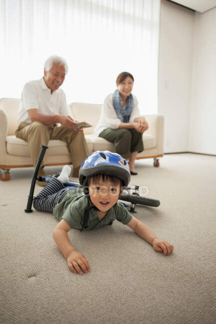 Мальчик лежит на полу с велосипедом — стоковое фото