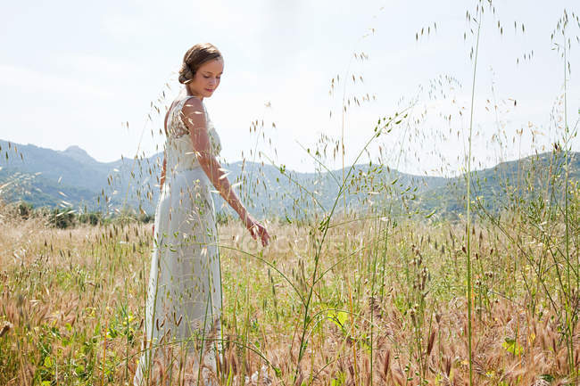 Невеста в свадебном платье одна в поле — стоковое фото