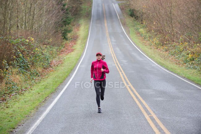 Женщина бежит по сельской дороге — стоковое фото