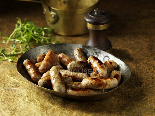 Rustic still life with cocktail sausages in metal serving dish — Stock Photo
