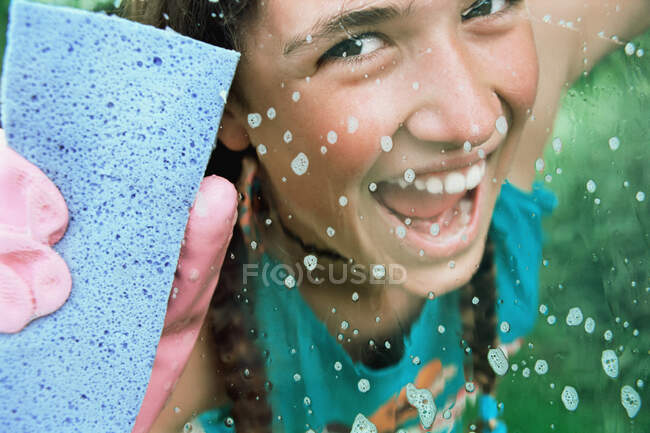 Chica de vidrio de limpieza con esponja - foto de stock