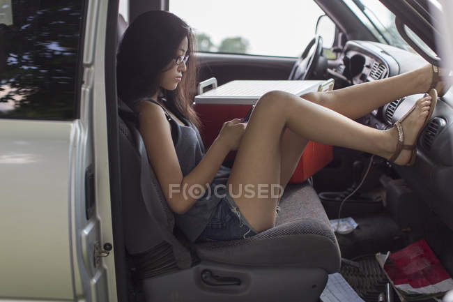 Portrait of young girl in pick up truck looking at smartphone — Stock Photo