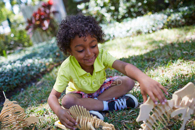 Мальчик играет с игрушками скелета динозавра — стоковое фото