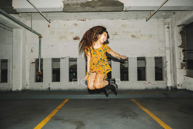 Молодая женщина прыгает в воздухе на крытой парковке — стоковое фото