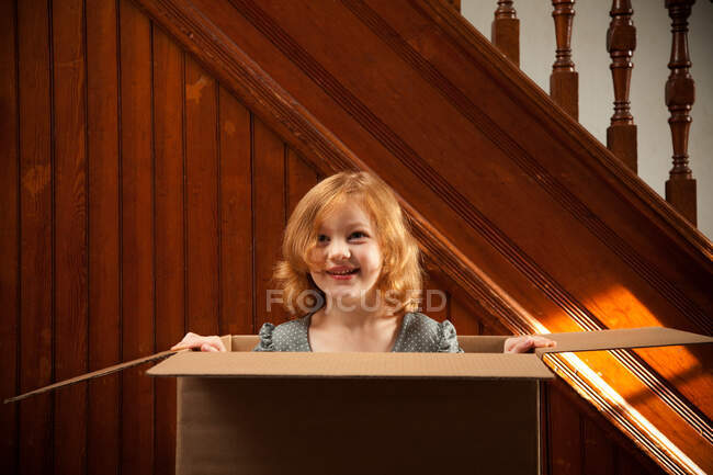 Retrato de menina escondida em caixa de papelão — Fotografia de Stock