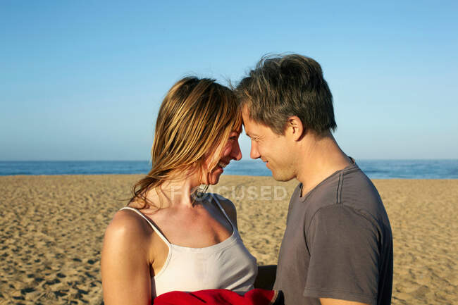 Casal adulto médio relaxante cabeça a cabeça na praia — Fotografia de Stock