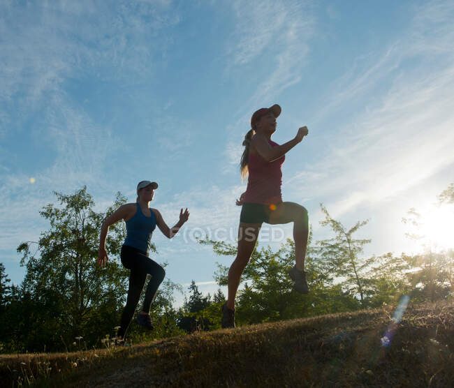 Teenage girls running together in field — Stock Photo