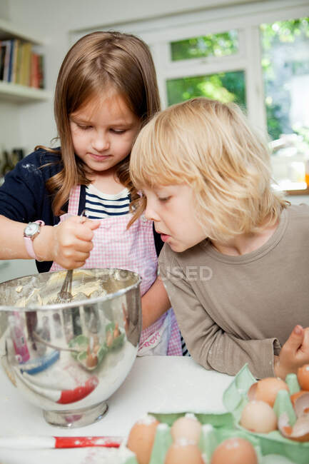 Garçon regarder soeur mélanger ingrédients gâteau — Photo de stock