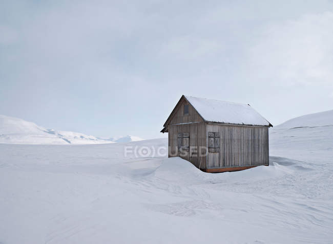 Celeiro na colina coberta de neve com céu nublado — Fotografia de Stock