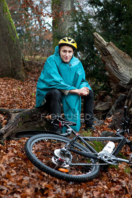 Young man sitting with bicycle in forest — Stock Photo