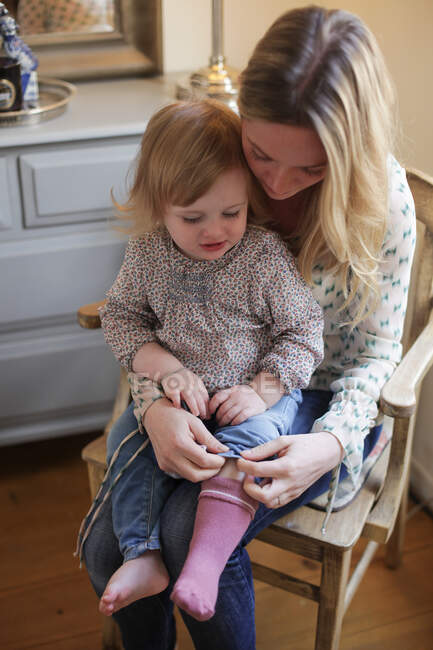 Мама помогает дочери надеть носки — стоковое фото
