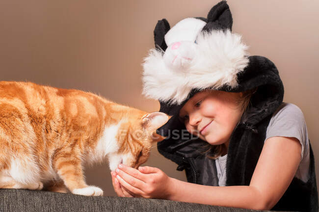 Mädchen im Katzenkostüm füttert Katze — Stockfoto