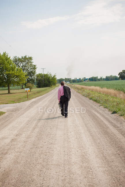 Empresário caminhando por uma estrada de terra — Fotografia de Stock