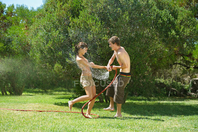 Adolescentes brincando com mangueira de água — Fotografia de Stock