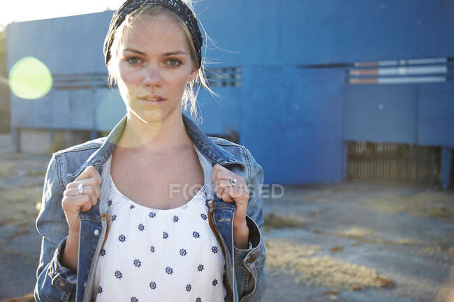 Portrait of woman holding jacket collar in industrial district — Stock Photo