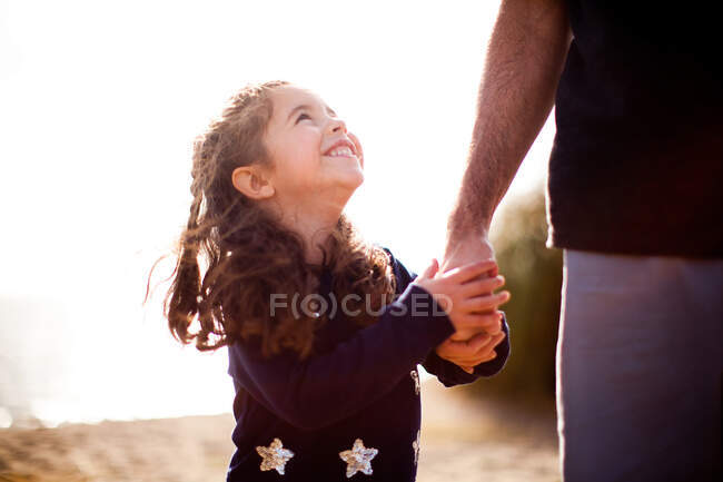 Menina segurando a mão do pai, olhando para cima — Fotografia de Stock