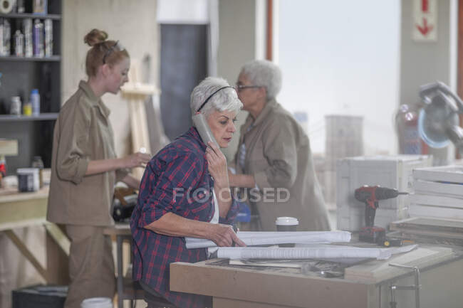 Cape Town, South Africa, woman working in wood workshop, talking on the phone — Stock Photo