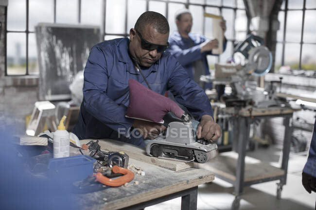 Cape Town, South Africa, machinist in workshop sanding down wood with safety goggles — Stock Photo