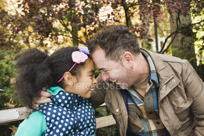Padre e hija cabeza a cabeza sonriendo - foto de stock