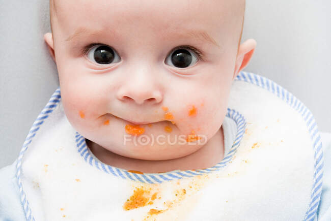 Bébé avec de la nourriture sur le visage — Photo de stock