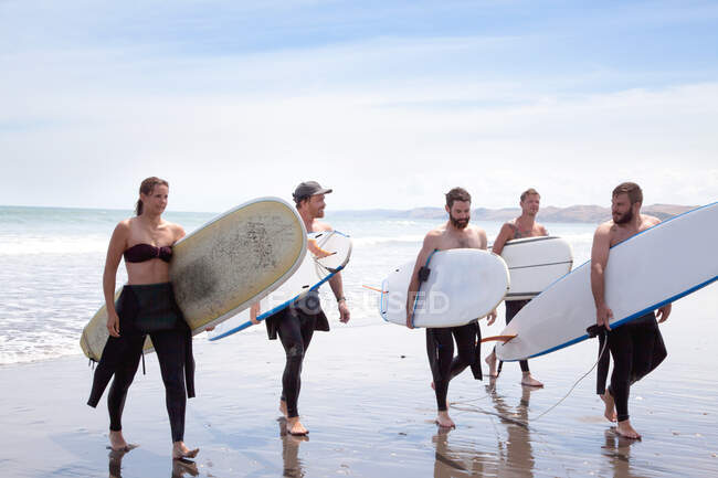 Група чоловіків і жінок-серфінгістів відходять з моря з дошками для серфінгу. — стокове фото