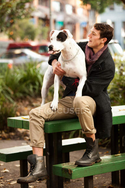 Чоловік сидить з собакою на столі для пікніка — стокове фото