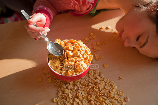 Mujer joven con cereales para el desayuno derramados - foto de stock