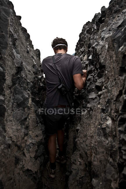 Man in rock crevice, Black Tusk, Garibaldi Provincial Park, British Columbia, Canadá - foto de stock