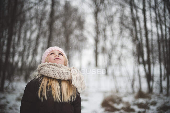Fille portant chapeau et écharpe levant les yeux en hiver — Photo de stock