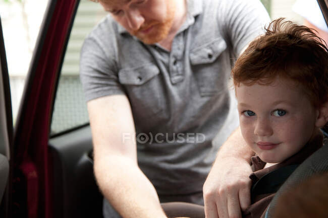 Батько закріплює сина в машині — стокове фото