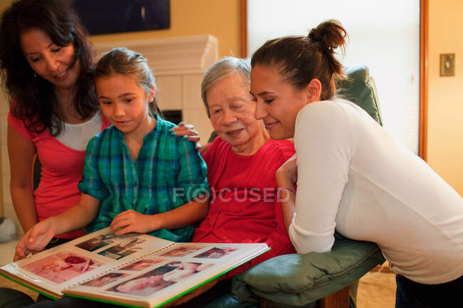Família de três gerações olhando para álbum de fotos — Fotografia de Stock