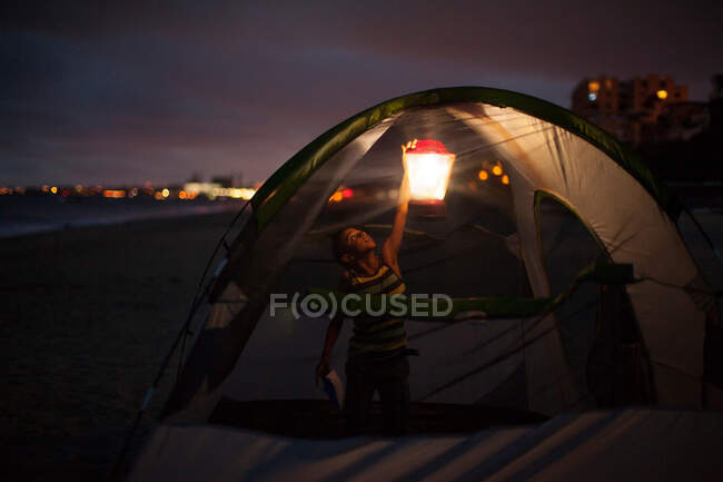 Menino na tenda com colo à noite, Huntington Beach, Califórnia, EUA — Fotografia de Stock