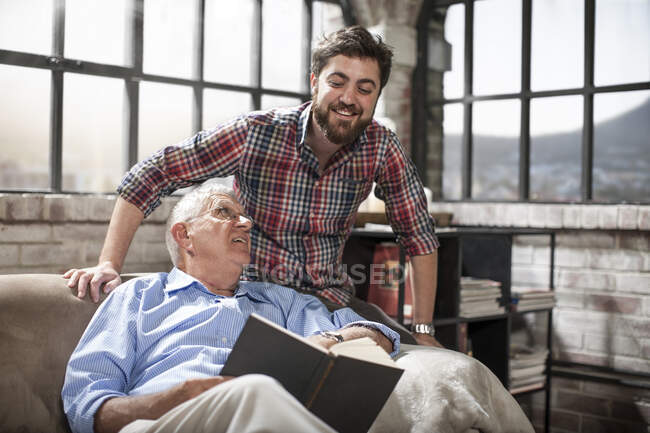 Отец и сын читают книгу дома — стоковое фото