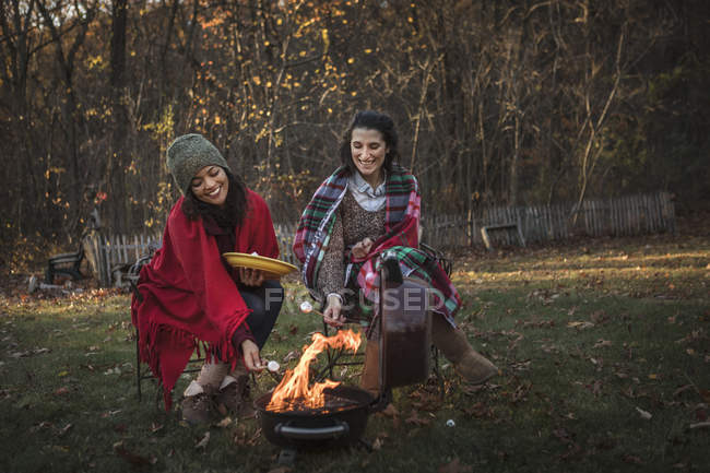 Two female friends toasting marshmallows on campfire — Stock Photo