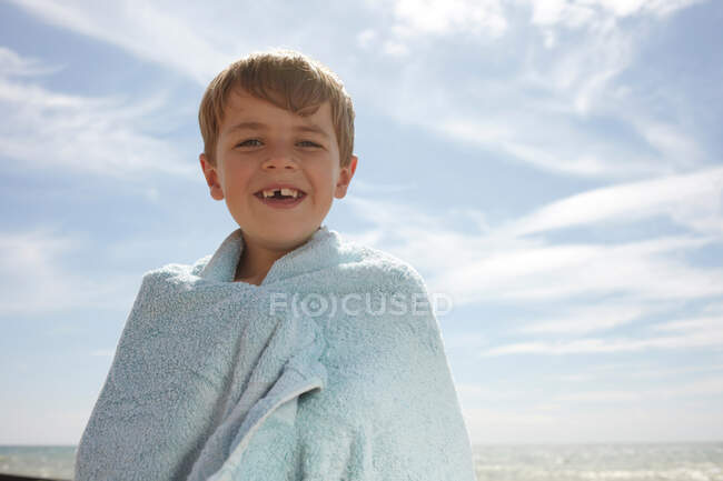 Мальчик у моря, завернутый в полотенце — стоковое фото