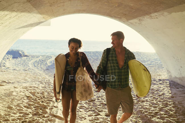 Surfing couple walking in underpass at Newport Beach, California, USA — Stock Photo