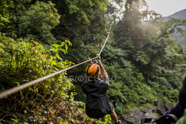 Hombre en tirolina en el bosque, Ban Nongluang, provincia de Champassak, Paksong, Laos - foto de stock