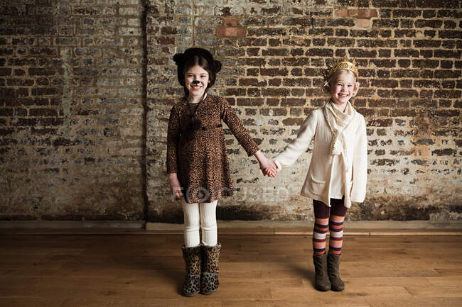 Young girls dressed up as cat and queen, holding hands — Stock Photo