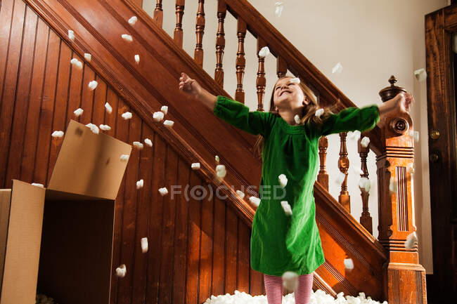Girl playing with packing material from cardboard box — Stock Photo