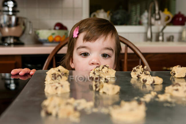 Close up portrait of young female toddler looking at currant cakes — Stock Photo