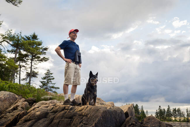 Senior man and dog looking out to coast of Maine, USA — Stock Photo