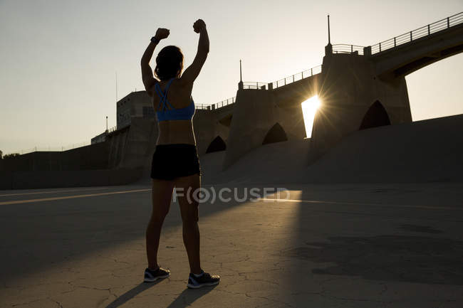 Жіночий спортсмен, який розтягується на заході сонця, Ван Найс, Каліфорнія, Уса. — стокове фото