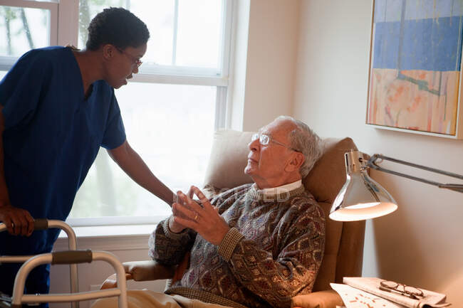 Медсестра доглядає за старшим чоловіком вдома — стокове фото
