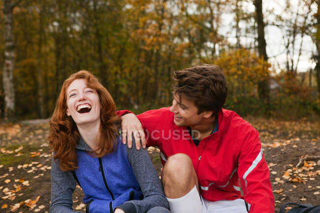 Young couple in sportswear laughing in forest — Stock Photo