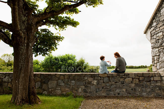 Vater und Sohn sitzen auf Steinmauer — Stockfoto