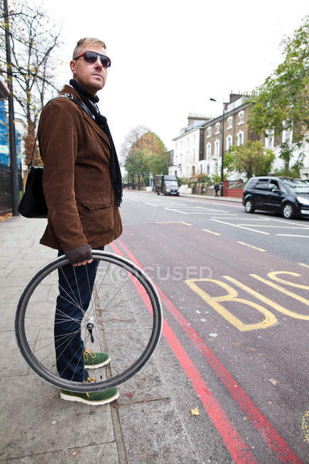 Ciclista sosteniendo rueda de bicicleta - foto de stock