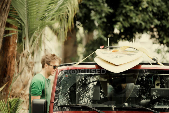 Man tying surfboards to roof of car — Stock Photo