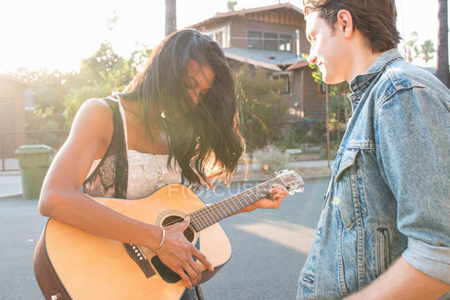 Jovem casal ao ar livre, jovem mulher tocando guitarra — Fotografia de Stock