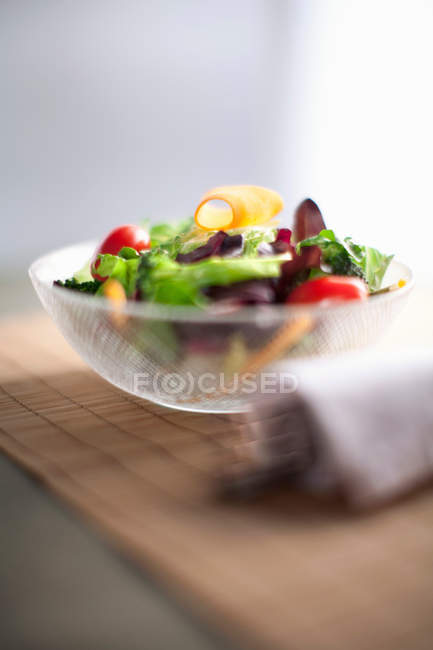 Schüssel mit frischem Salat auf Holzbrett — Stockfoto